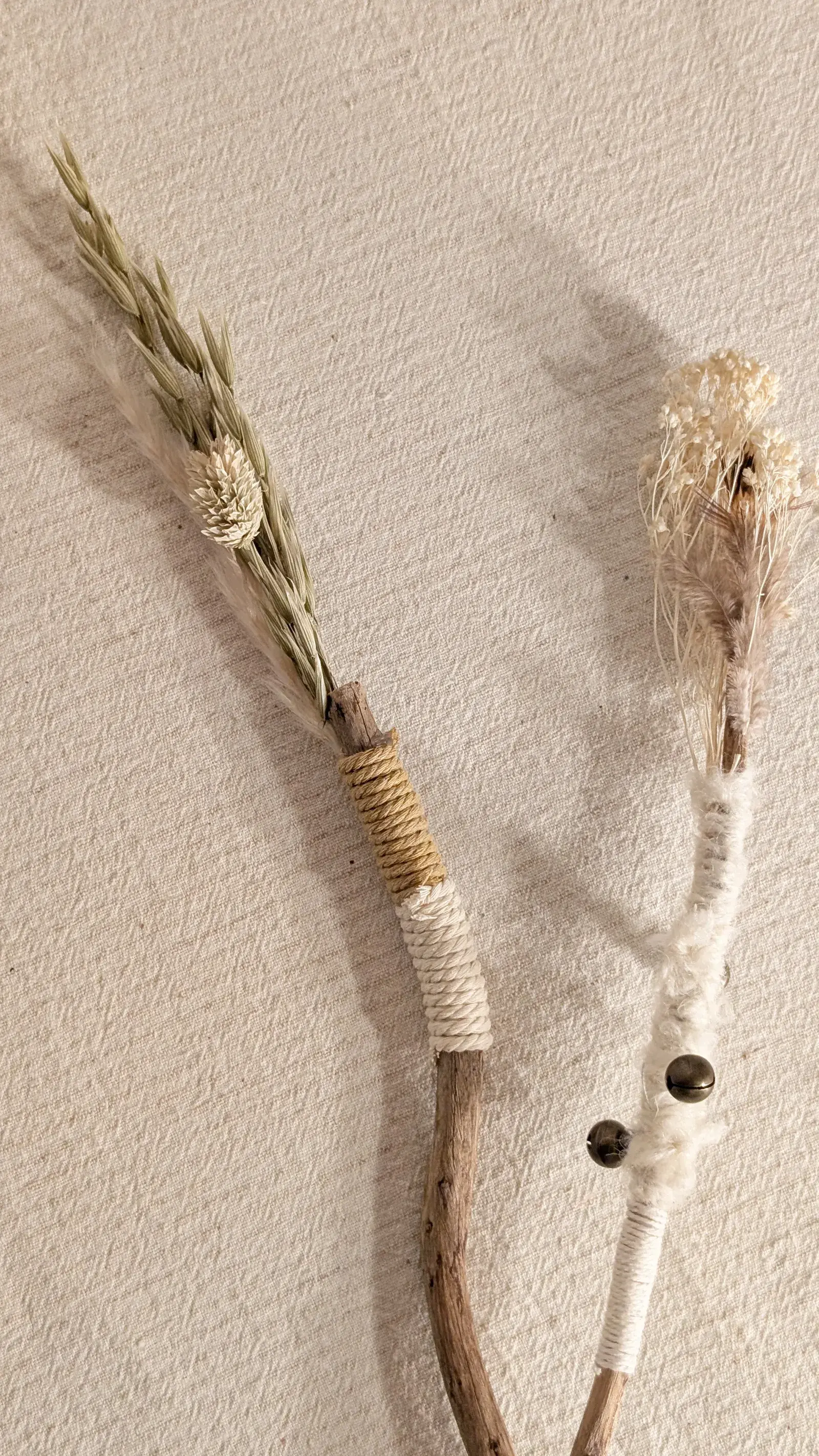 Handmade nature wand decorated with ribbons, feathers, dried flowers, and natural materials.