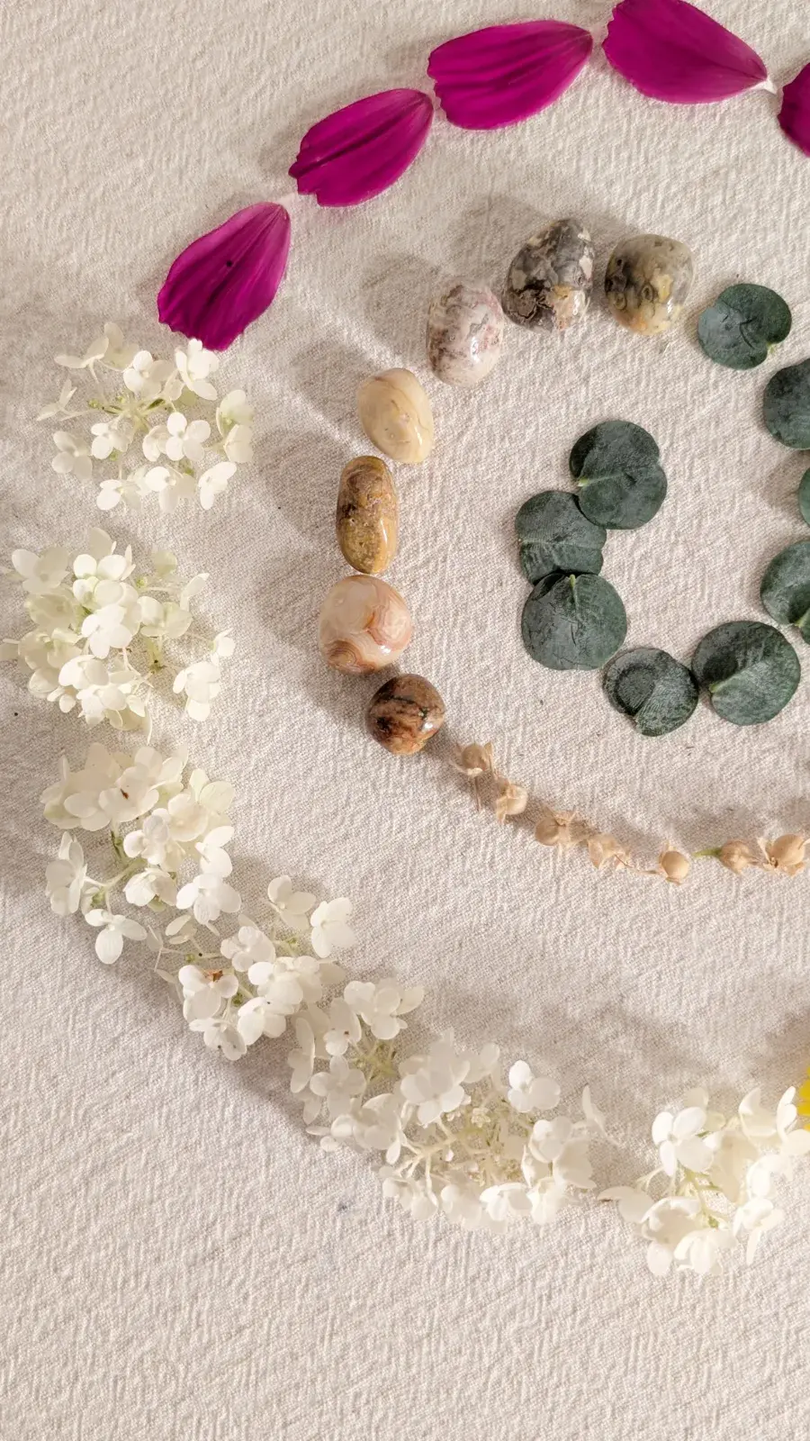 Nature mandala arranged from flowers, leaves, pebbles, and small woodland treasures in a circular pattern.