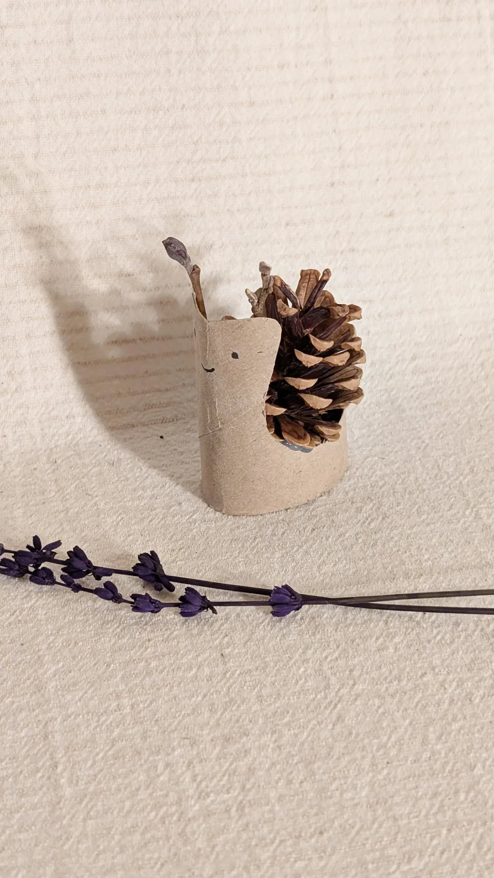 Handmade pinecone snail created from a pinecone and cardboard tube with painted details.