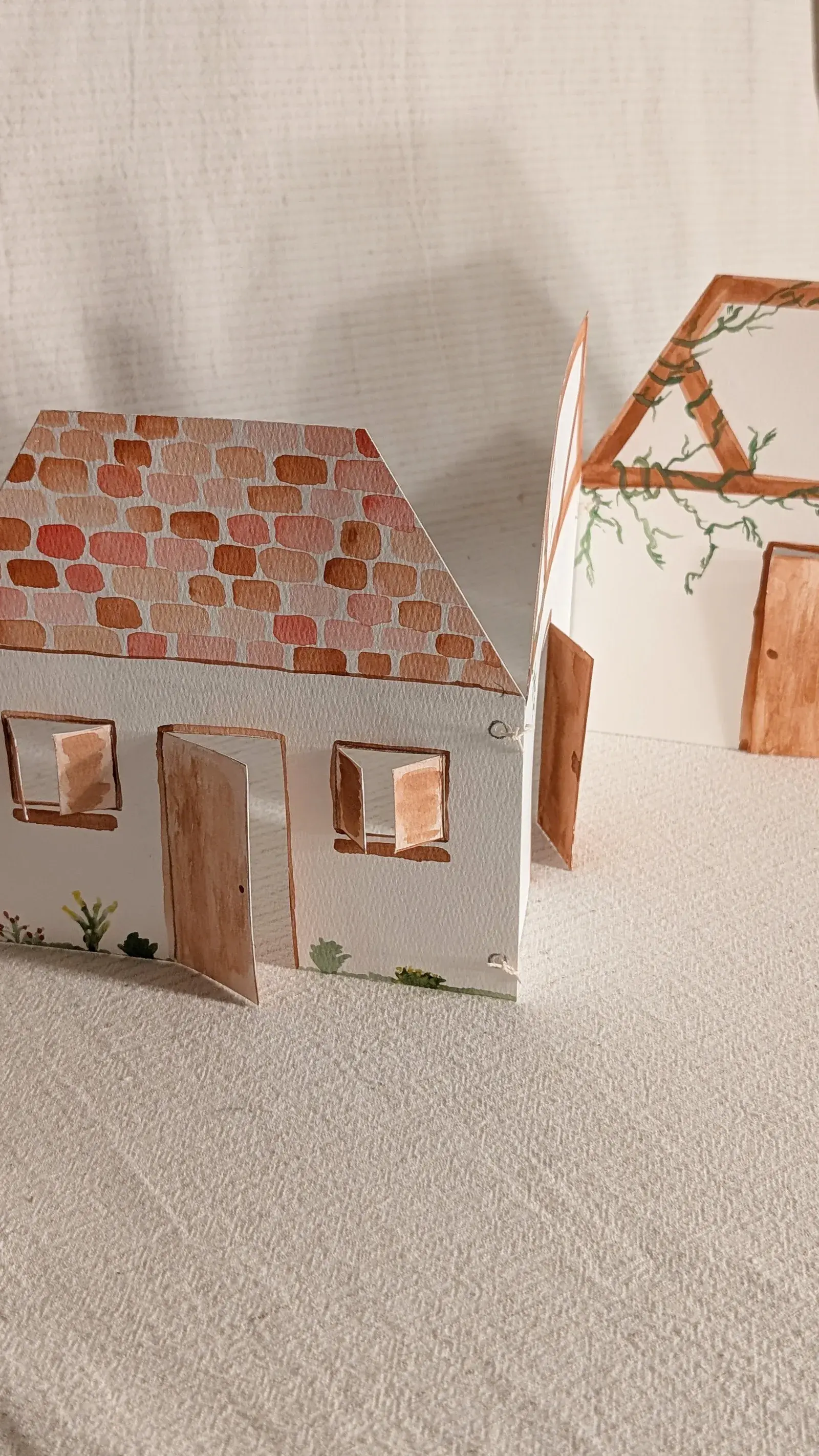 Printable fold-out paper Woodland Cottage assembled into an accordion-style miniature house with decorated rooms.