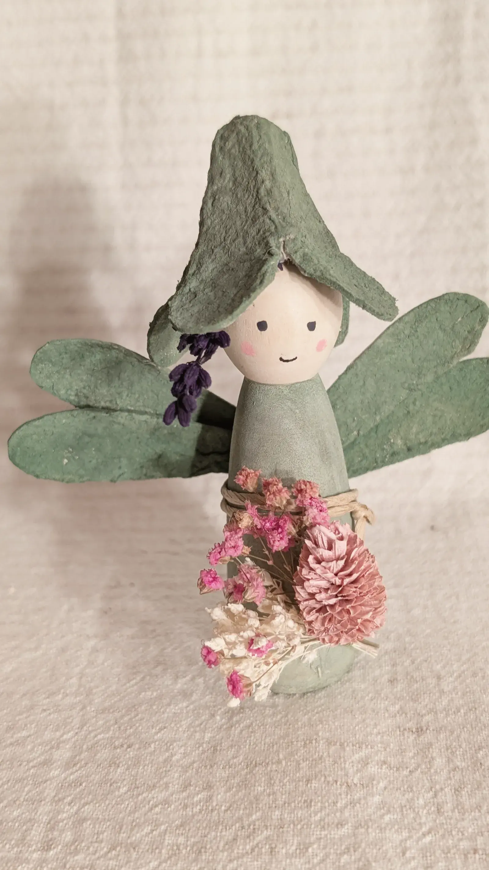 Handmade flower fairy made from a wooden peg doll with an egg carton flower hat and dried flowers.